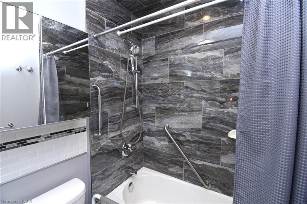 Modern bathroom featuring a walk-in shower with dark linear-pattern tile surround, chrome fixtures, and glass enclosure - 10 Craddock Boulevard, Jarvis, ON - Indoor Photo Showing Bathroom