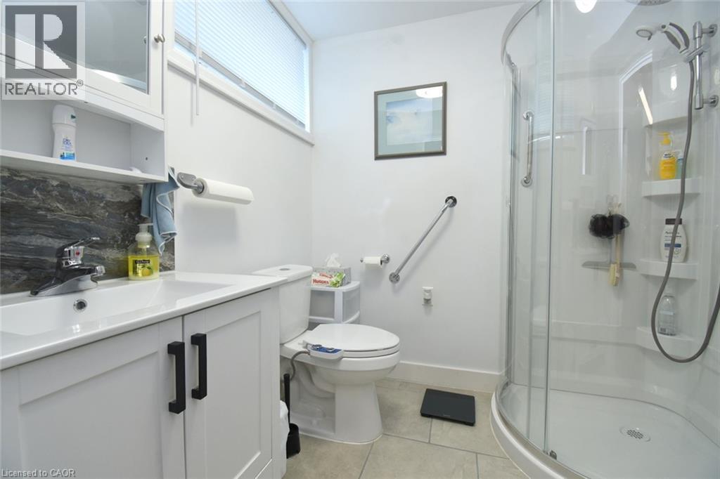 Modern bathroom featuring a sleek walk-in shower with frameless glass enclosure and chrome fixtures, white subway tile surround, and rainfall showerhead - 10 Craddock Boulevard, Jarvis, ON - Indoor Photo Showing Bathroom