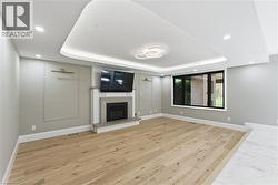 Spacious room featuring wood-finish flooring, a contemporary fireplace with a tile surround and stone mantel, and a large window providing ample natural light - 