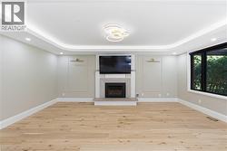 Spacious room featuring light wood-finish flooring and a contemporary linear fireplace with a stone hearth - 