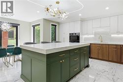 Kitchen featuring a substantial central island with green cabinetry and a light-toned countertop - 