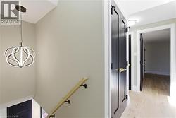 Hallway featuring wood-finish flooring, light-toned walls, and a modern ceiling light fixture - 
