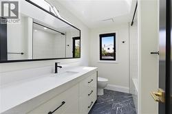 Contemporary bathroom featuring a spacious vanity with an integrated sink, white countertop, and matte black fixtures - 