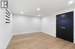 Recessed lighting illuminates a room featuring light wood-finish flooring, white walls, and bright white trim - 