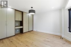 Built-in cabinetry featuring a desk area and drawers, wood-finish flooring, recessed lighting, and a modern ceiling fixture - 