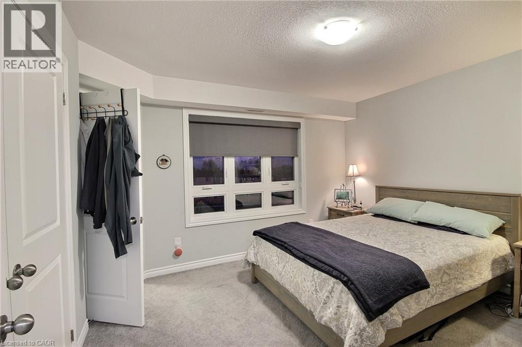 Spacious bedroom retreat featuring a wood-finish bed frame, neutral carpeting, and abundant natural light from multi-pane windows - 287 Chapel Hill Drive, Kitchener, ON - Indoor Photo Showing Bedroom