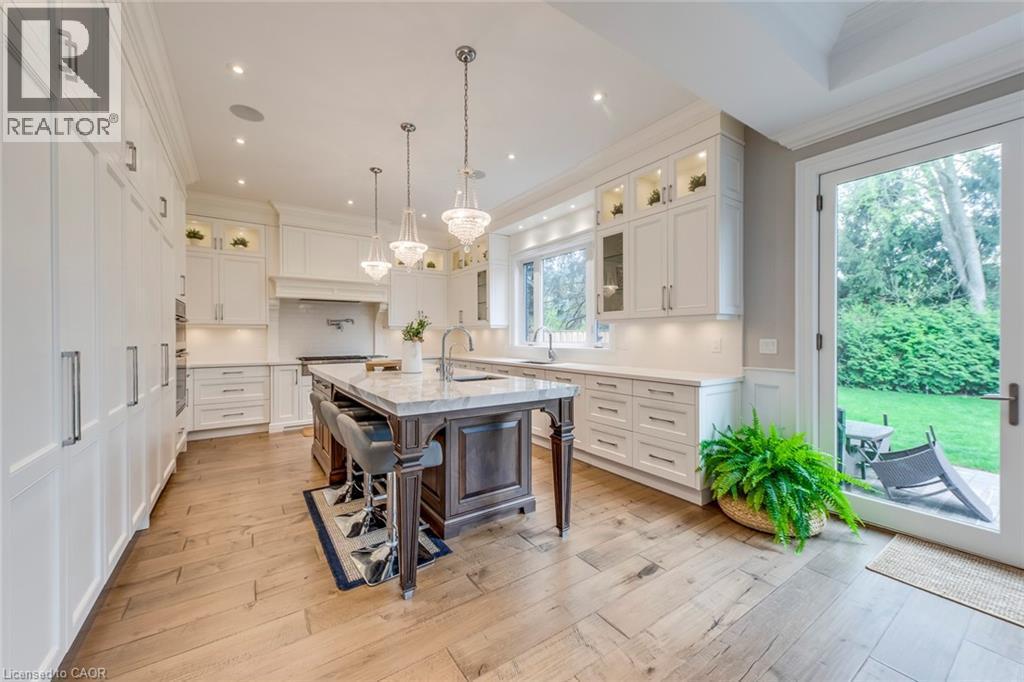 Gourmet kitchen featuring a large central island with seating, white shaker cabinetry, light wood-finish flooring, recessed lighting, and direct access to an exterior patio - 436 Willis Drive, Oakville, ON - Indoor Photo Showing Kitchen With Upgraded Kitchen