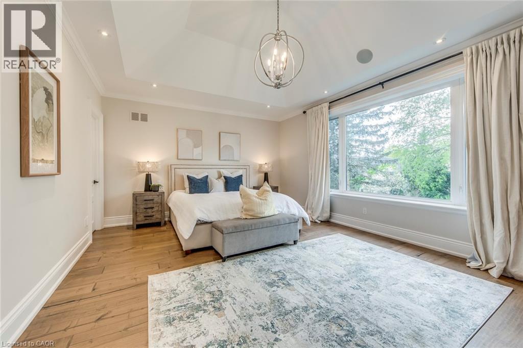 Spacious room featuring wood-finish flooring, a large picture window, tray ceiling with recessed lighting, and a spherical chandelier - 436 Willis Drive, Oakville, ON - Indoor Photo Showing Bedroom