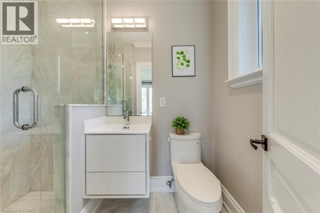 Bathroom featuring a frameless glass shower enclosure, a wall-mounted vanity with integrated sink, contemporary lighting fixtures, a window with trim, and a white paneled door with dark hardware - 436 Willis Drive, Oakville, ON - Indoor Photo Showing Bathroom