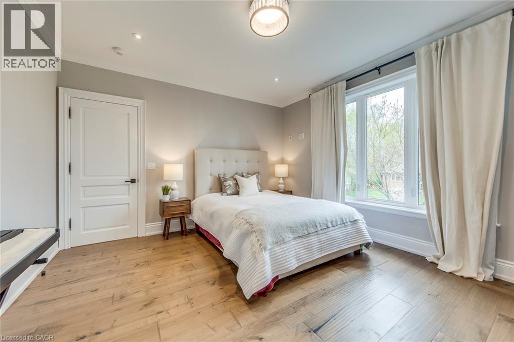 Bedroom featuring wood-finish flooring, a large window with white trim, a decorative ceiling light fixture, recessed lighting, and a solid white interior door - 436 Willis Drive, Oakville, ON - Indoor Photo Showing Bedroom