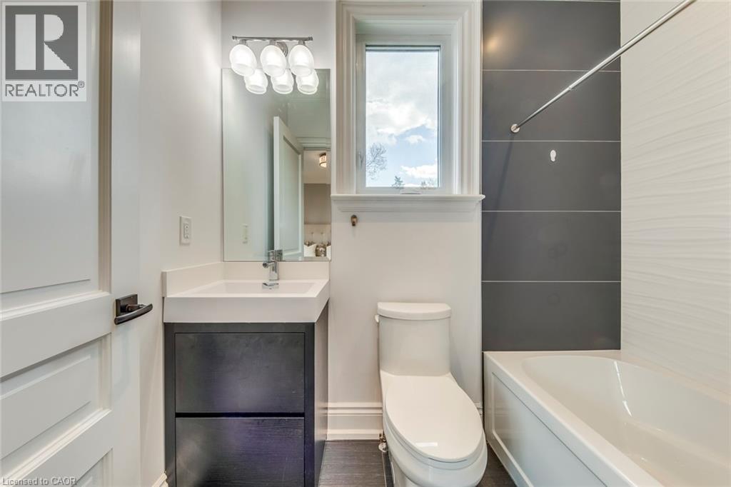 Bathroom featuring a white bathtub, gray rectangular wall tiles, and wood-finish flooring - 436 Willis Drive, Oakville, ON - Indoor Photo Showing Bathroom