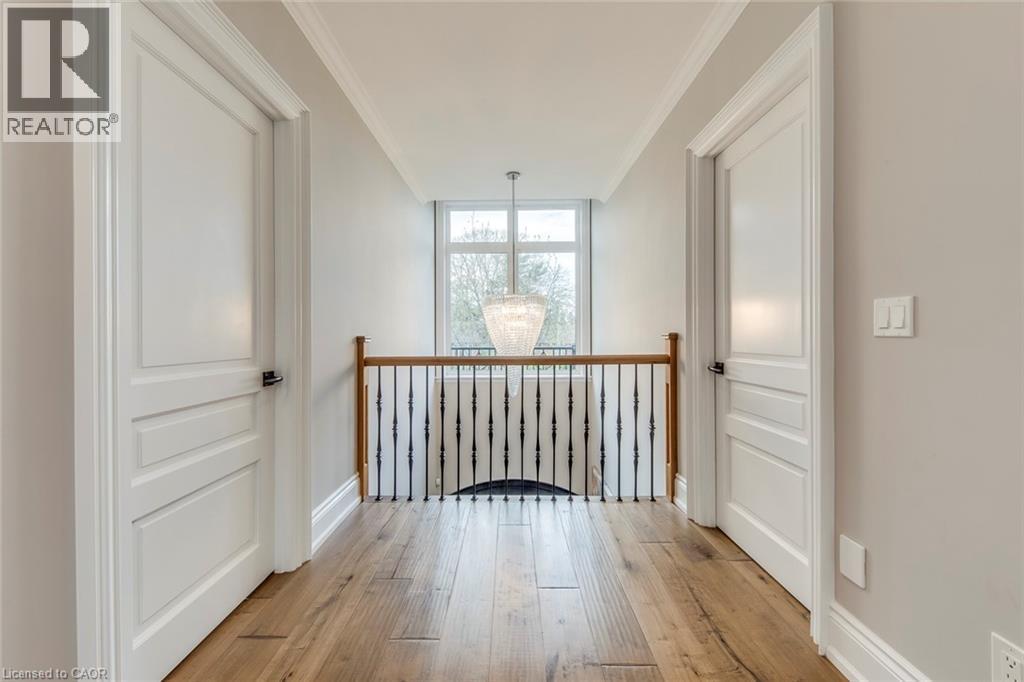 Upper-level hallway featuring hardwood flooring, crown molding, white panel doors, and a wrought iron and wood handrail - 436 Willis Drive, Oakville, ON - Indoor Photo Showing Other Room