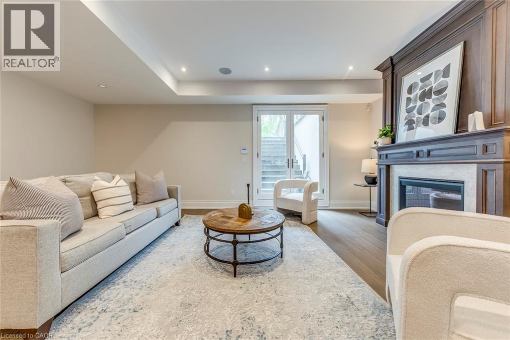 Recessed lighting illuminates the open living space featuring wood-finish flooring, a detailed fireplace with a stone surround, and light-toned walls - 436 Willis Drive, Oakville, ON - Indoor Photo Showing Living Room With Fireplace