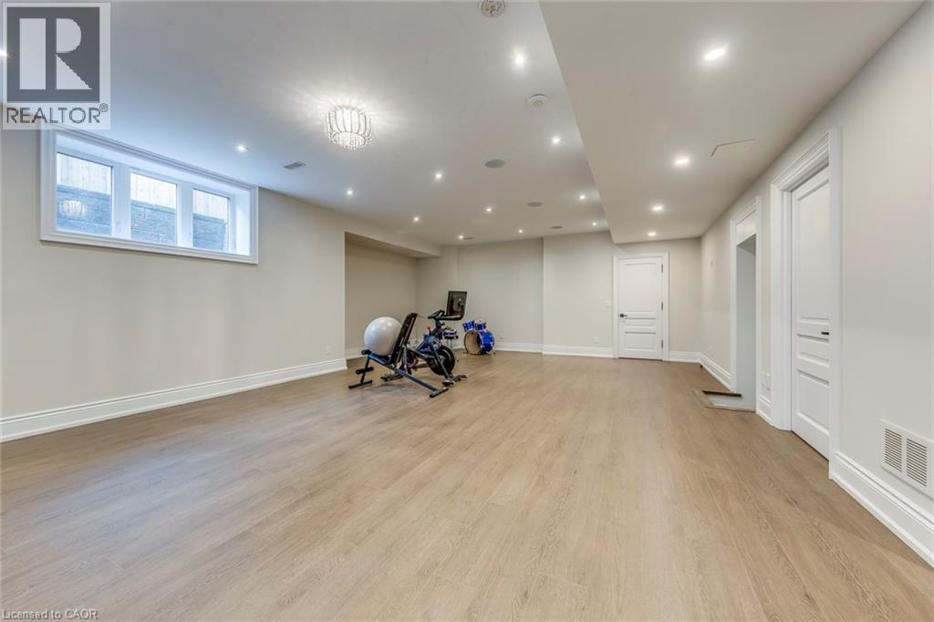 Spacious lower-level room featuring wood-finish flooring, recessed lighting, a built-in window, and two paneled doors with dark hardware - 436 Willis Drive, Oakville, ON - Indoor