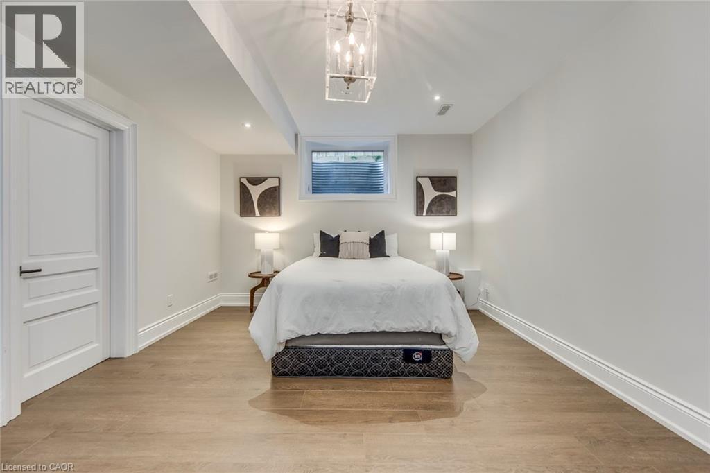 Recessed lighting illuminating wood-finish flooring, white trim, and a window with a metal grate - 436 Willis Drive, Oakville, ON - Indoor Photo Showing Bedroom