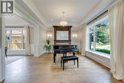 Elegant formal living space showcasing light wood-finish flooring, coffered ceiling detail, and crystal chandelier - 