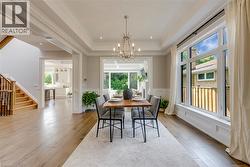 Tray ceiling with a decorative chandelier, expansive window wall, light wood-finish flooring, wainscoting, and a built-in planter - 