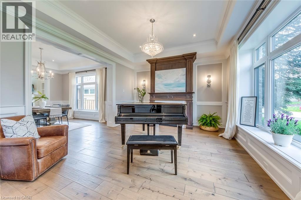 Formal living area featuring wood-finish flooring, a decorative wood mantel, recessed lighting, a chandelier, and expansive windows with custom millwork - 436 Willis Drive, Oakville, ON - Indoor Photo Showing Living Room With Fireplace