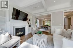 Coffered ceiling with recessed lighting, built-in shelving, fireplace with stone surround, wood-finish flooring, and crown molding - 