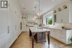 White cabinetry with panel-front appliances, wood-finish flooring, and a central island with a stone countertop - 