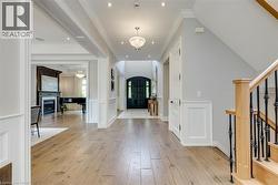 Hardwood-finish flooring throughout, wainscoting details, recessed lighting, and a prominent dark wood entry door - 