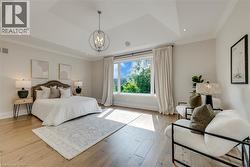 Tray ceiling with recessed lighting and a central chandelier, wood-finish flooring, and a large window - 