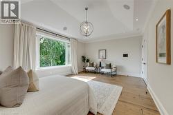 Expansive window, tray ceiling, recessed lighting, wood-finish flooring, and a contemporary chandelier - 