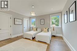 Light-toned walls, wood-finish flooring, two windows with white trim, recessed lighting, and a decorative ceiling fixture - 
