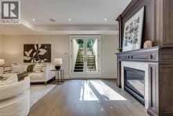 Sophisticated primary suite showcasing hardwood flooring, a gas fireplace with built-in cabinetry and framed artwork display, French doors opening to exterior spaces, recessed ceiling lighting, and a - 