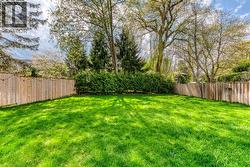 Expansive lawn area, perimeter fencing, mature trees, and dense shrubbery along the rear border - 
