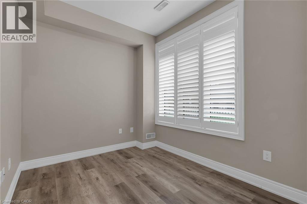 Room featuring a window with white louvered shutters, light neutral wall paint, white baseboards, and wood-finish flooring - 2 Waterview Lane, Grimsby, ON - Indoor Photo Showing Other Room