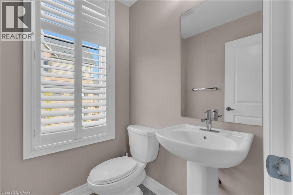Pedestal sink with chrome faucet, a white toilet, and window with plantation shutters - 2 Waterview Lane, Grimsby, ON - Indoor Photo Showing Bathroom