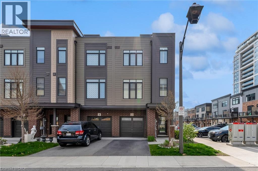 Contemporary townhouse exterior featuring a multi-tone facade with dark siding, tan panels, and brick accents - 2 Waterview Lane, Grimsby, ON - Outdoor With Facade