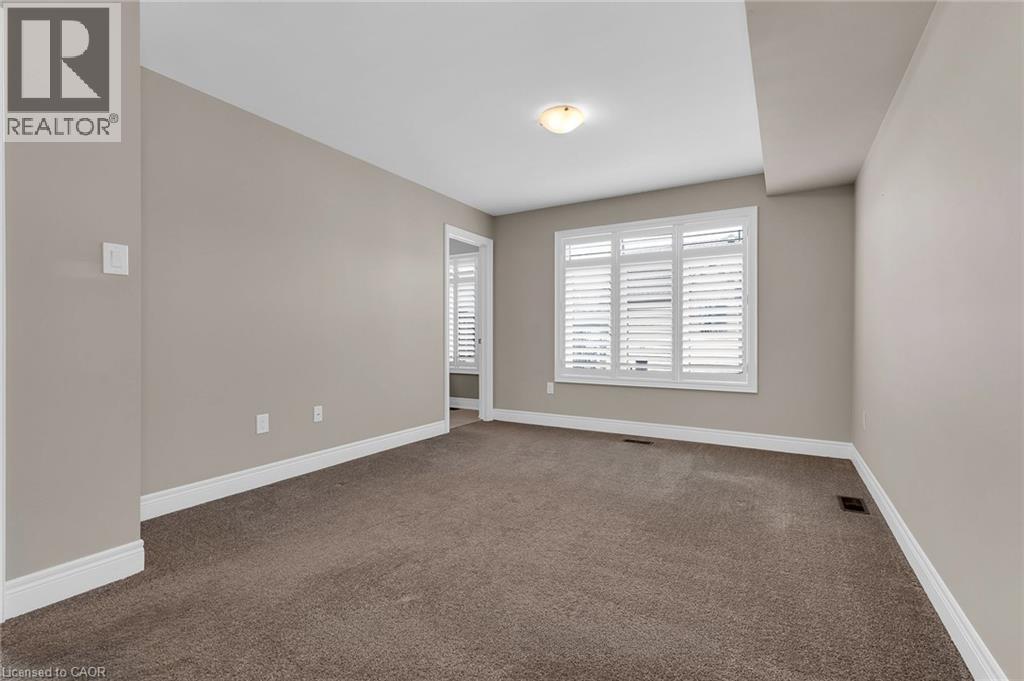Carpeted interior space with a window featuring white plantation shutters and a ceiling-mounted light fixture - 2 Waterview Lane, Grimsby, ON - Indoor Photo Showing Other Room