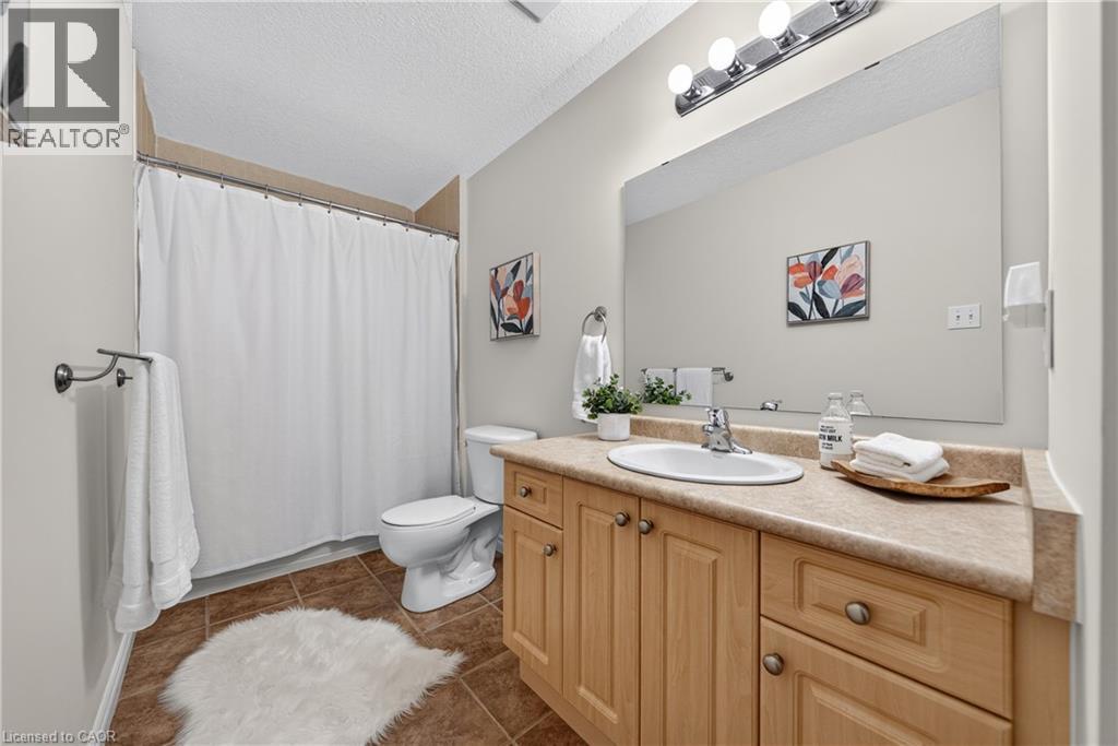 Bathroom featuring a light wood-finish vanity with an integrated sink, a large wall-mounted mirror, overhead vanity lighting, and ceramic tile flooring - 24 Knack Lane, Cambridge, ON - Indoor Photo Showing Bathroom