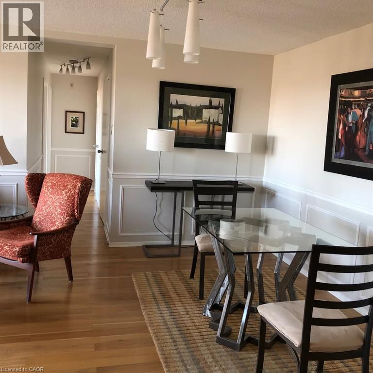 Open-concept living area featuring wood-finish flooring, wainscoting, and a multi-light ceiling fixture - 30 Blue Springs Drive Unit# Ph3, Waterloo, ON - Indoor Photo Showing Dining Room