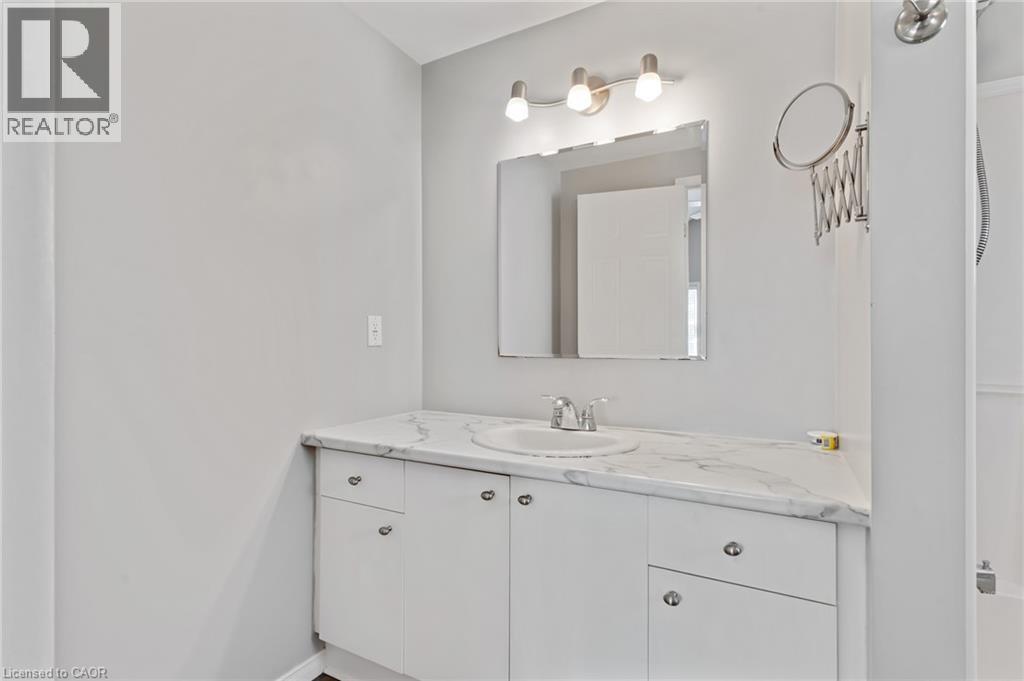 White vanity with a single basin sink and a stone-finish countertop - 129 Kovac Road, Cambridge, ON - Indoor Photo Showing Bathroom