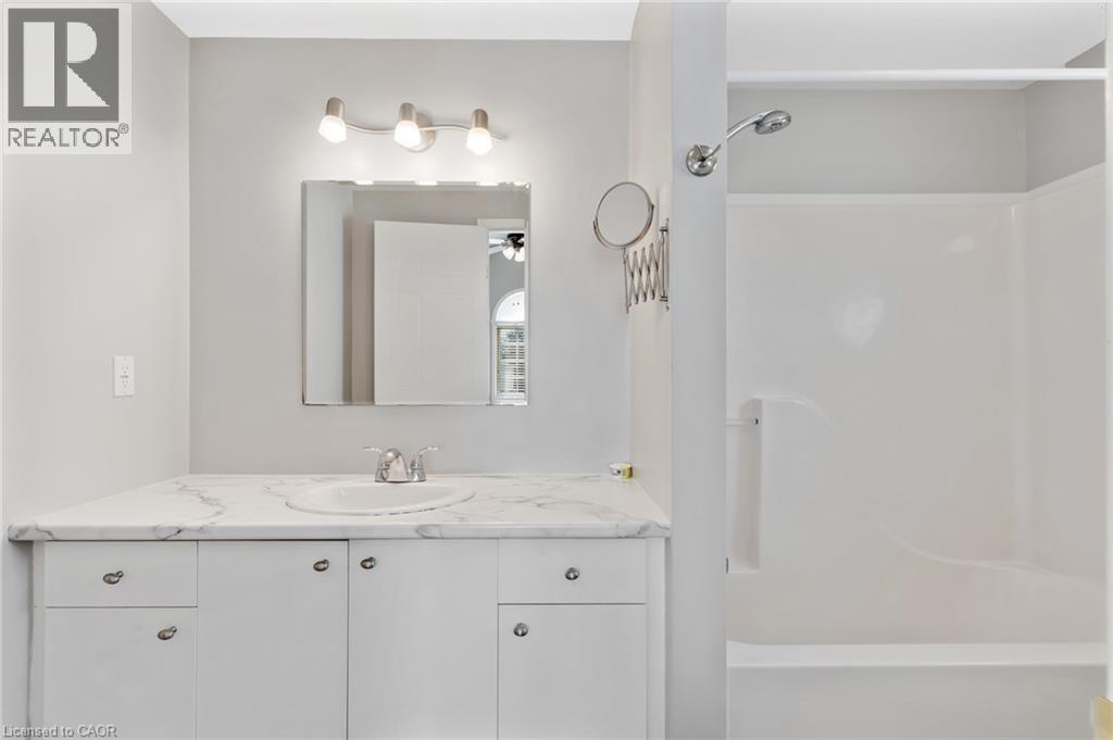 Bathroom featuring a white vanity with a single basin, a stone-finish countertop, and white cabinetry - 129 Kovac Road, Cambridge, ON - Indoor Photo Showing Bathroom