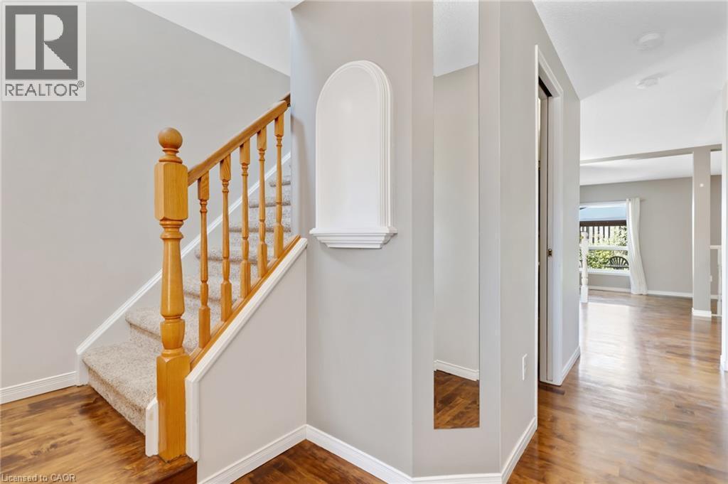 Carpeted staircase with wood banister, wood-finish flooring, and light gray wall paint - 129 Kovac Road, Cambridge, ON - Indoor Photo Showing Other Room
