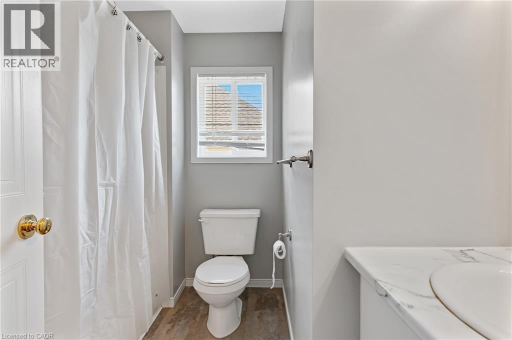 Bathroom featuring a single window with blinds, a white toilet, and wood-finish flooring - 129 Kovac Road, Cambridge, ON - Indoor Photo Showing Bathroom