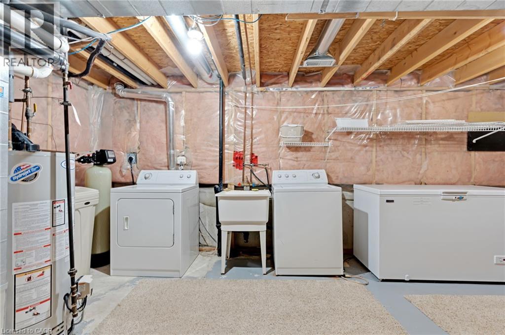 Utility area featuring exposed joist ceiling, insulated walls, concrete flooring, and an included laundry sink - 129 Kovac Road, Cambridge, ON - Indoor Photo Showing Laundry Room