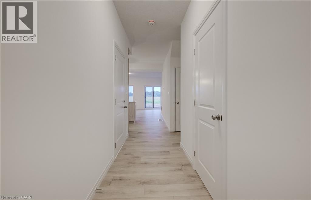 Hallway featuring light wood-finish flooring, white paneled doors with brushed nickel hardware, and neutral wall tones - 89 Rivergreen Crescent, Cambridge, ON - Indoor Photo Showing Other Room