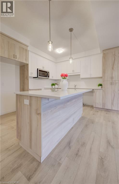 Modern kitchen featuring a central island with a light wood-finish base and a light-toned countertop - 89 Rivergreen Crescent, Cambridge, ON - Indoor Photo Showing Kitchen