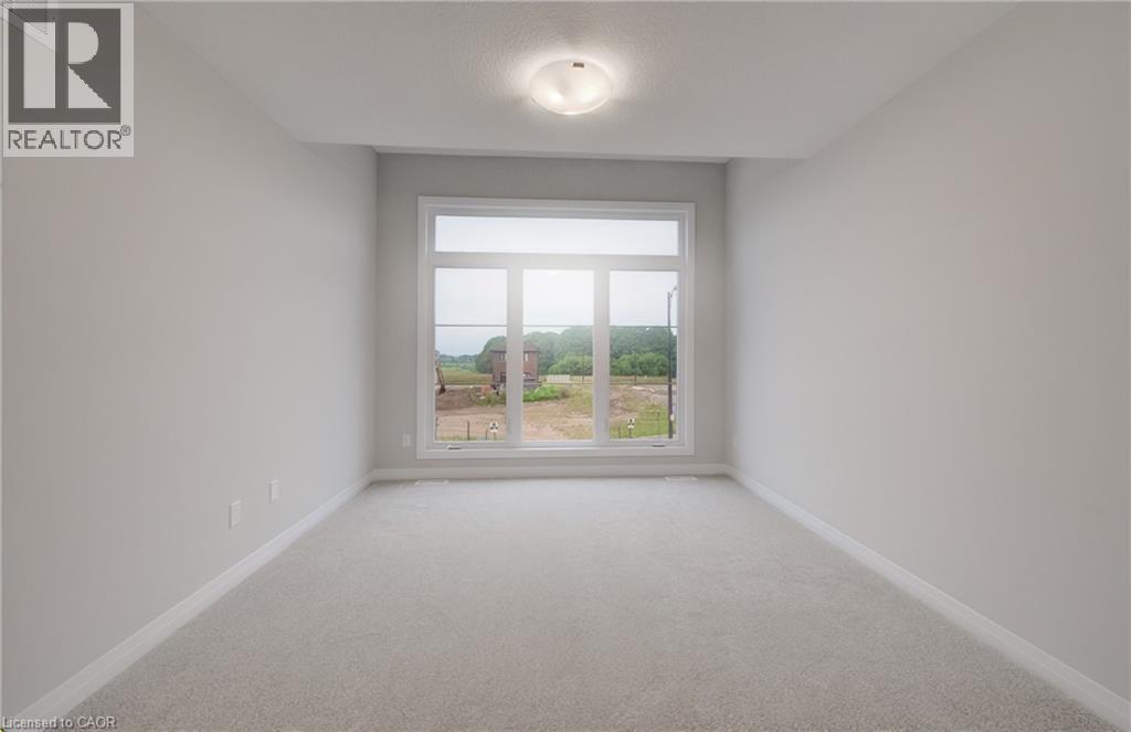 Bright interior space featuring a large multi-pane window, neutral-toned walls, plush carpeting, white baseboards, and a ceiling-mounted light fixture - 89 Rivergreen Crescent, Cambridge, ON - Indoor Photo Showing Other Room