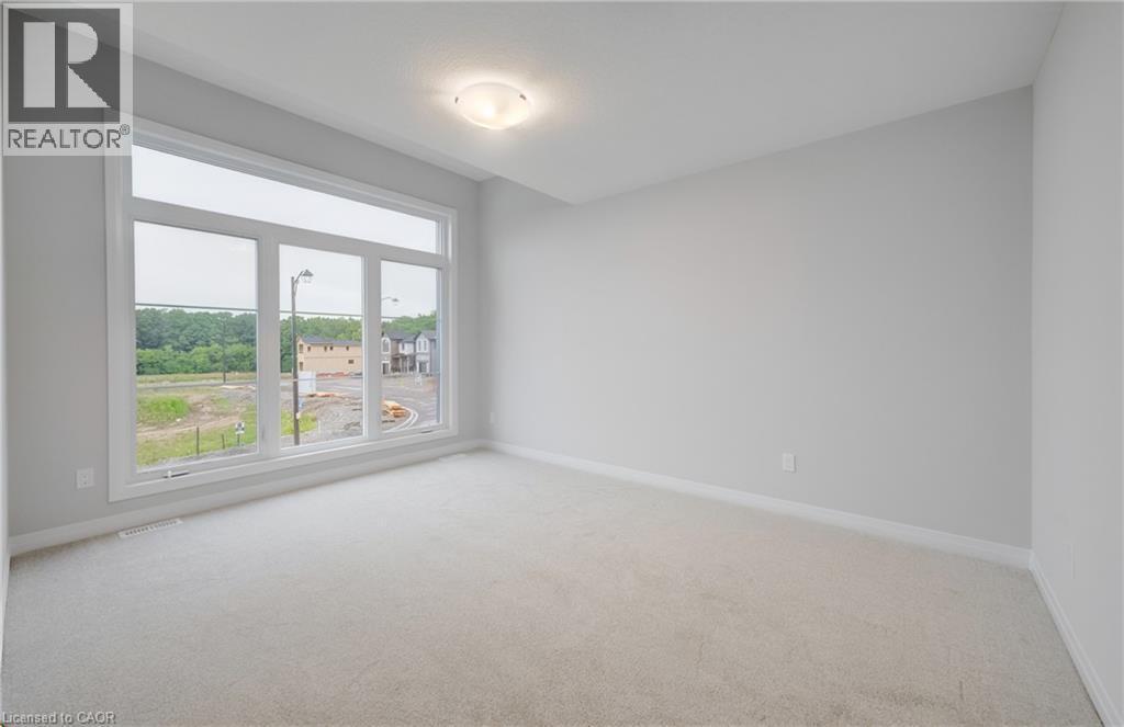 Expansive room featuring a large multi-pane window with white trim, light gray wall paint, light-colored carpeting, white baseboards, and a flush-mount ceiling light fixture - 89 Rivergreen Crescent, Cambridge, ON - Indoor Photo Showing Other Room