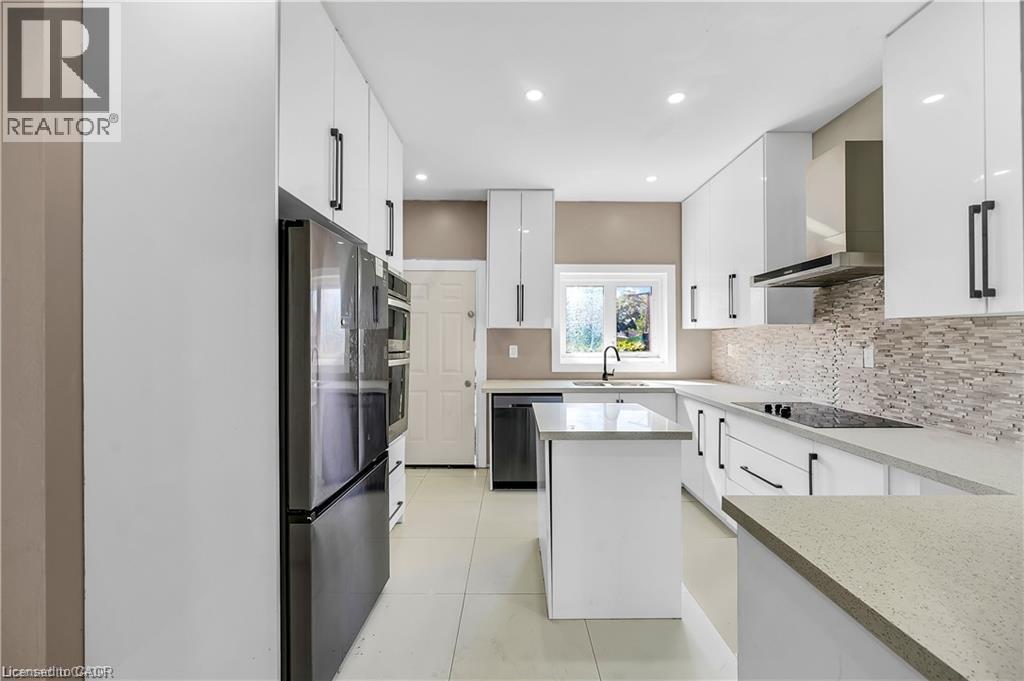 Modern galley kitchen featuring white cabinetry with integrated hardware, quartz countertops, and a mosaic tile backsplash - 334 Cannon Street E, Hamilton, ON - Indoor Photo Showing Kitchen With Upgraded Kitchen
