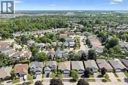 Residential neighborhood setting featuring multiple single-family homes, mature landscaping, paved streets, and a distant treeline -