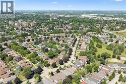 Expansive aerial encompassing a residential neighborhood with detached homes, mature tree coverage, clear skies, visible streets, and distant city structures -