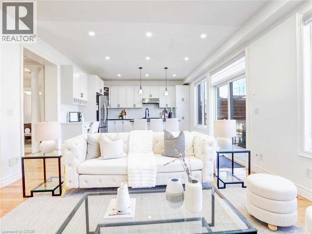 Open-concept living area featuring wood-finish flooring, recessed lighting, and a kitchen with white cabinetry - 584 Pinery Trail, Waterloo, ON - Indoor Photo Showing Other Room