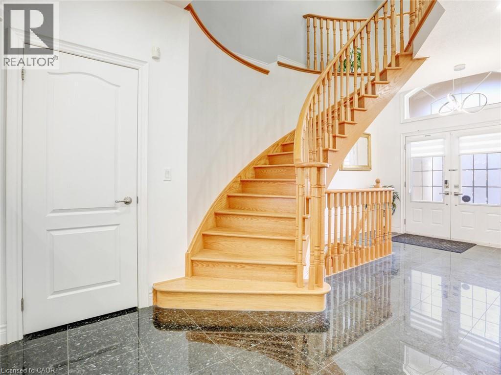Curved wood staircase with turned balusters, black polished flooring, and a white panel door - 584 Pinery Trail, Waterloo, ON - Indoor Photo Showing Other Room